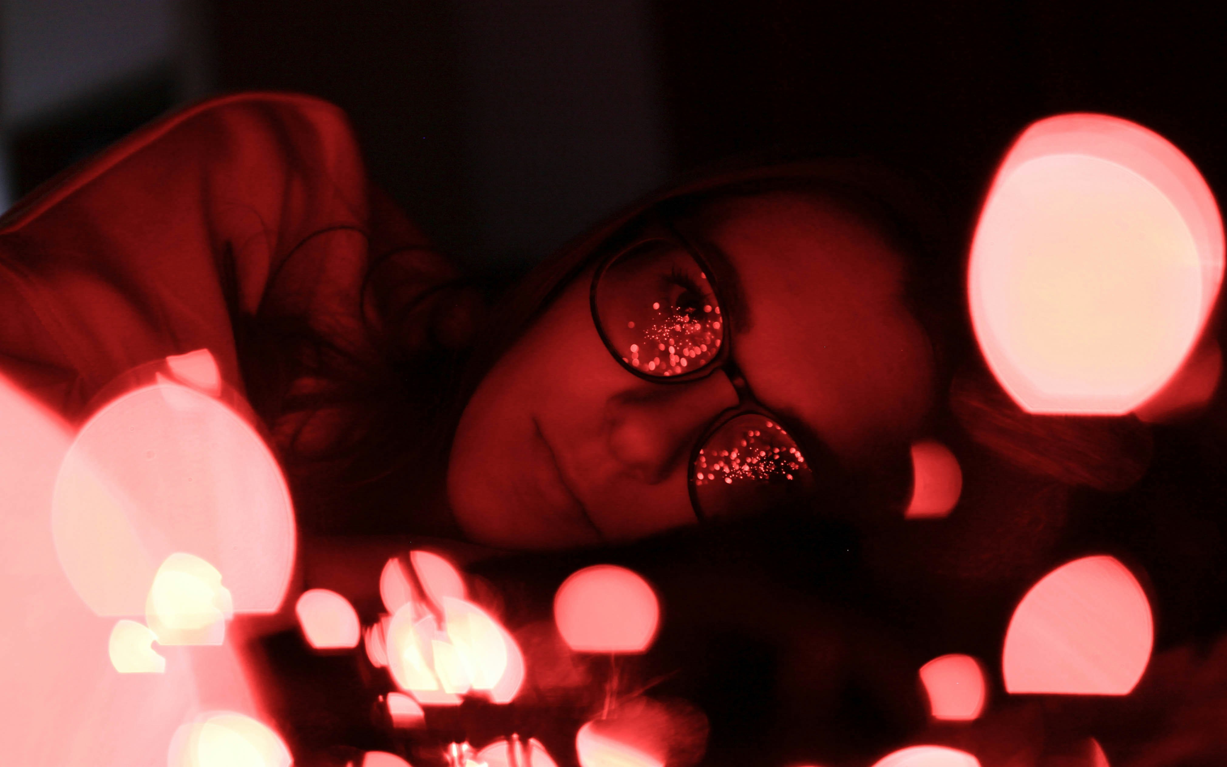 bokeh photography of woman wearing eyeglasses while lying